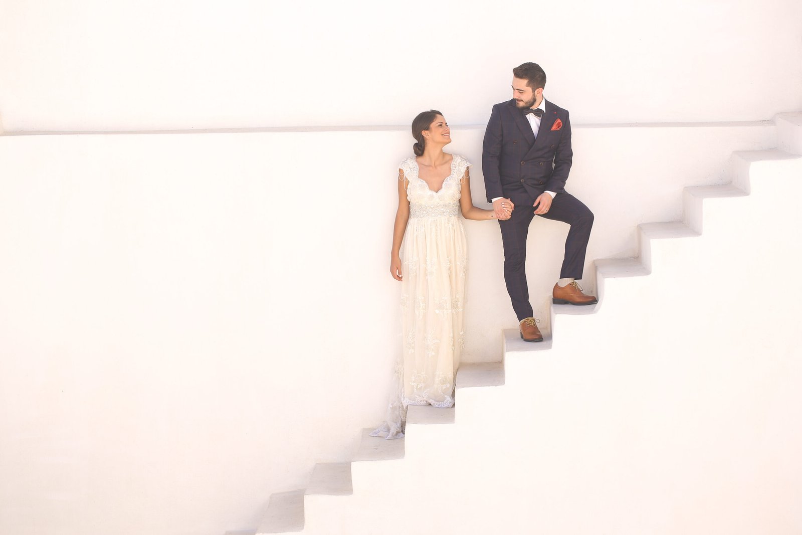 bride and groom posing on a white staircase