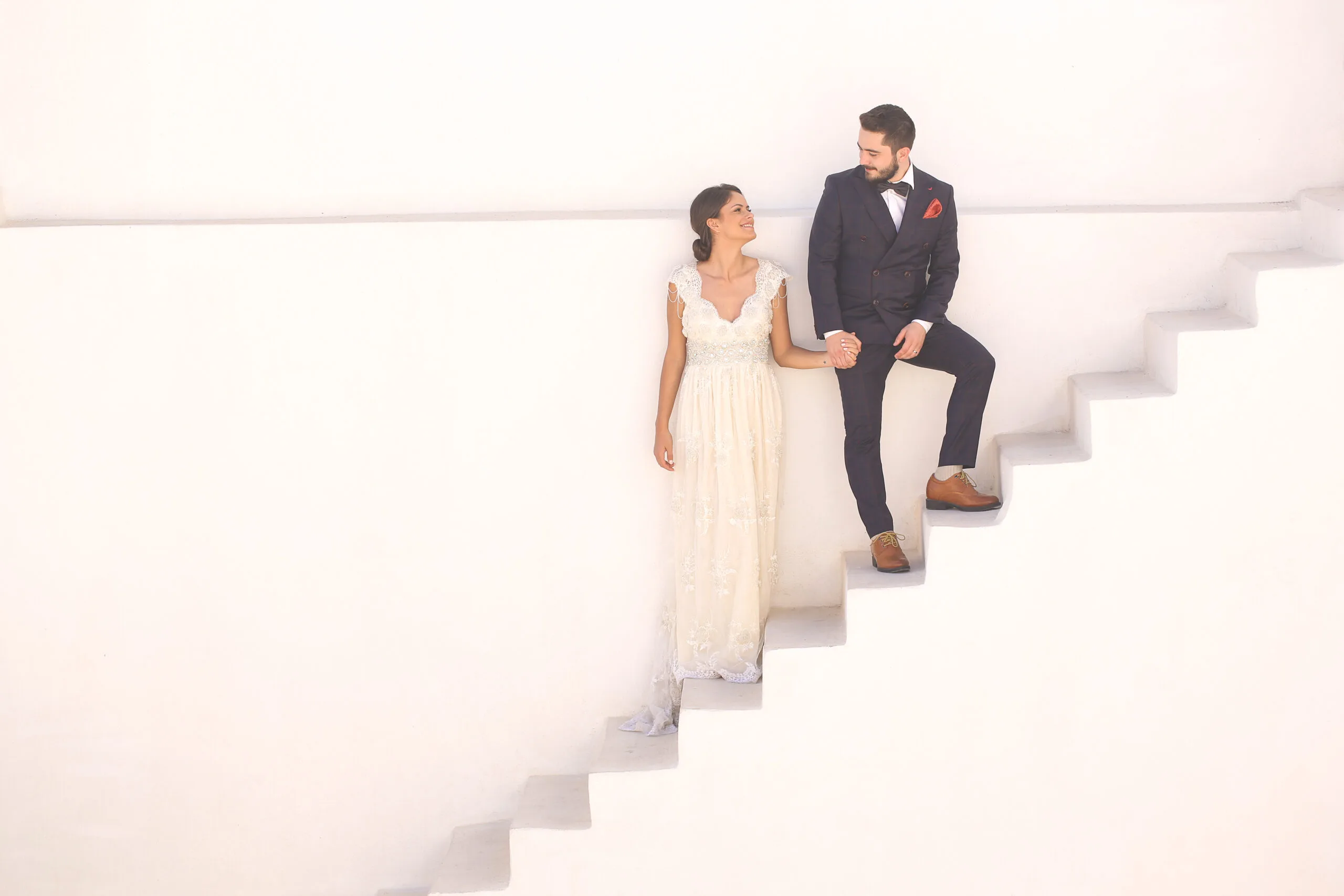 bride and groom posing on a white staircase