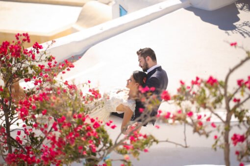 bride and groom sitting on the roof of a house in Santorini